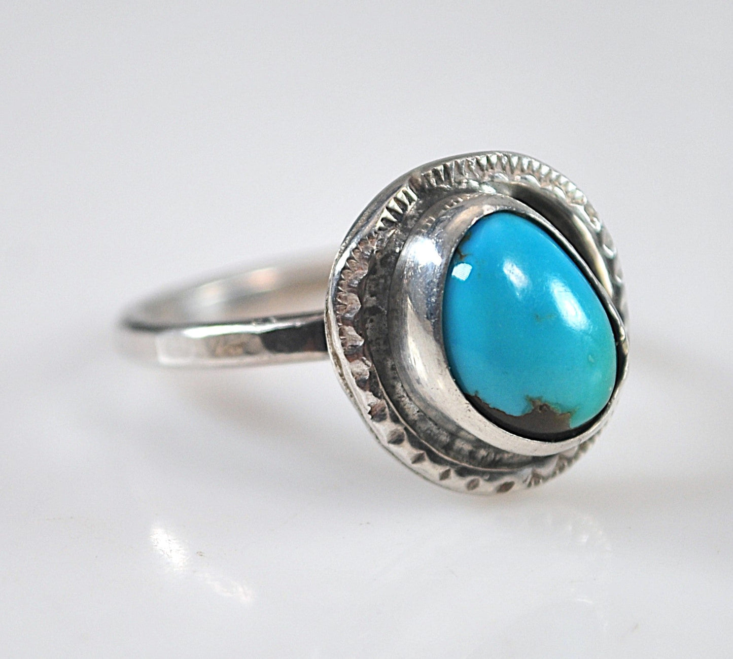 Silver ring with a turquoise stone on a white background